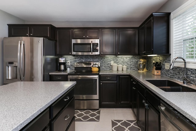 kitchen with light tile patterned floors, a sink, light countertops, appliances with stainless steel finishes, and tasteful backsplash