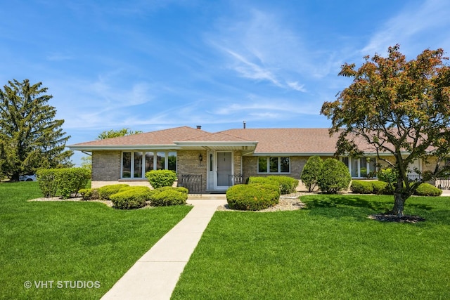 single story home featuring a front yard, brick siding, and a shingled roof