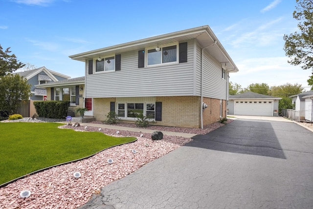 tri-level home featuring brick siding, an outbuilding, a garage, and a front lawn
