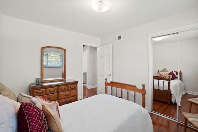 bedroom with a closet, dark wood-type flooring, and baseboards