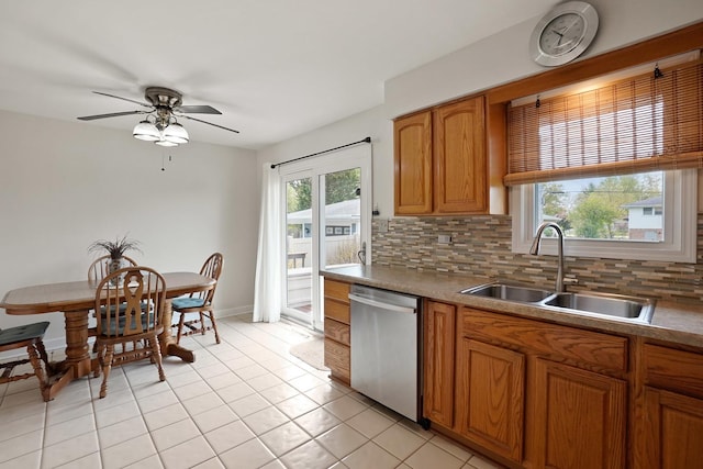 kitchen featuring stainless steel dishwasher, a sink, backsplash, and light tile patterned floors