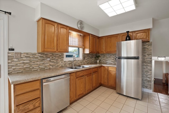 kitchen with appliances with stainless steel finishes, a sink, backsplash, and light tile patterned floors