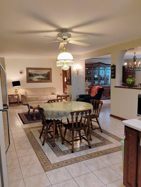 8856 Plainfield Rd, Brookfield, IL 60513 - dining space featuring light tile patterned floors, ceiling fan with notable chandelier, and arched walkways