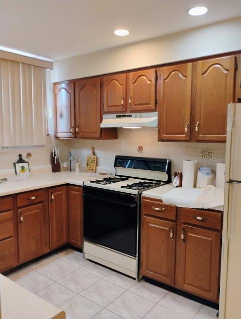 8856 Plainfield Rd, Brookfield, IL 60513 - kitchen featuring under cabinet range hood, light countertops, brown cabinets, and white appliances