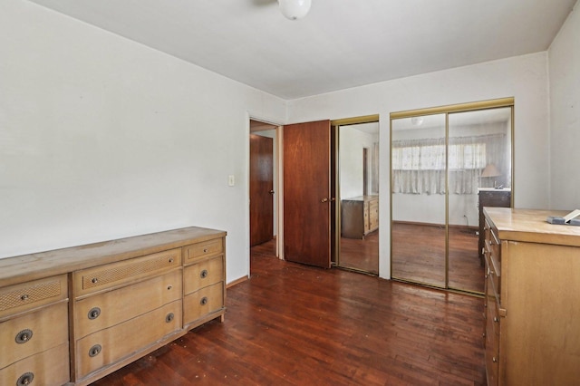 unfurnished bedroom featuring multiple closets and dark wood finished floors