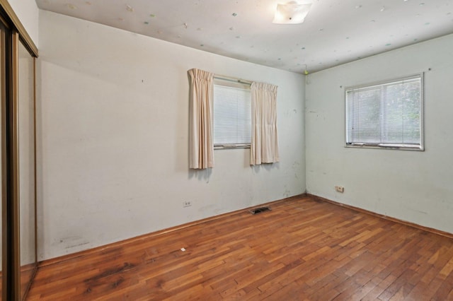 unfurnished bedroom with wood-type flooring and visible vents