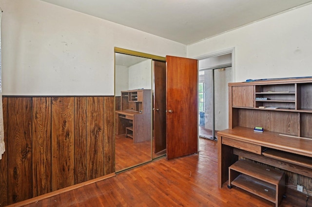 office area with wooden walls, a wainscoted wall, and wood finished floors