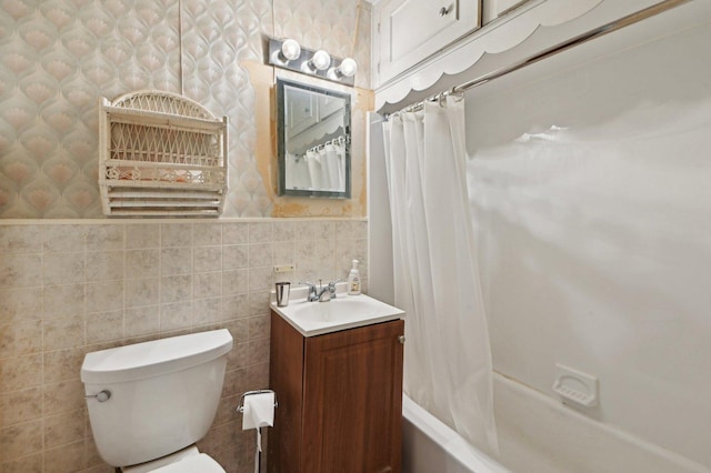 full bathroom with toilet, tile walls, a wainscoted wall, shower / tub combo with curtain, and wallpapered walls