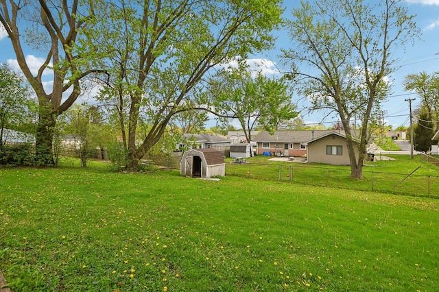 view of yard featuring a storage unit, a fenced backyard, and an outbuilding