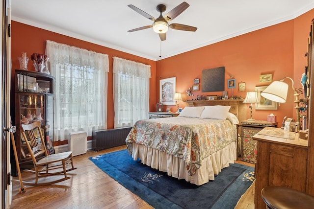 bedroom featuring crown molding, wood finished floors, and radiator heating unit
