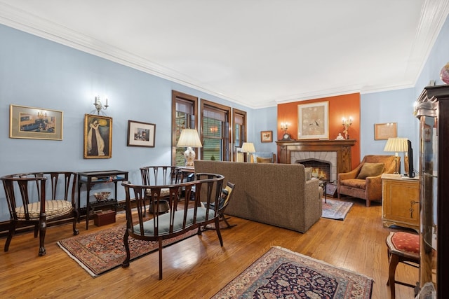 living room featuring crown molding, a tiled fireplace, and hardwood / wood-style floors