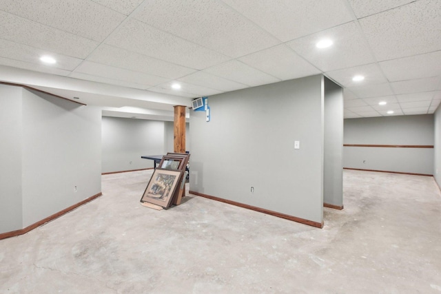 finished basement featuring a paneled ceiling, baseboards, and recessed lighting