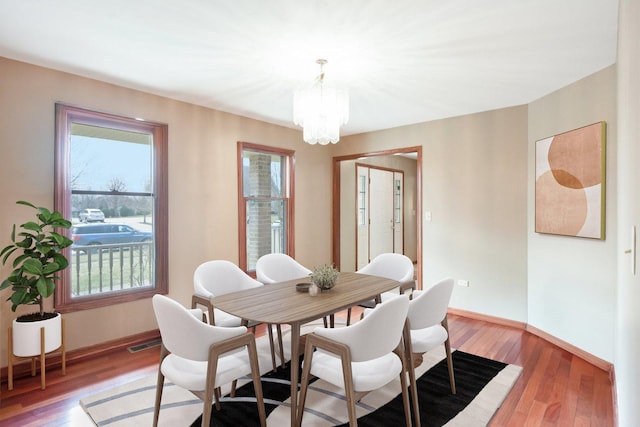 dining room featuring an inviting chandelier, light wood finished floors, baseboards, and visible vents