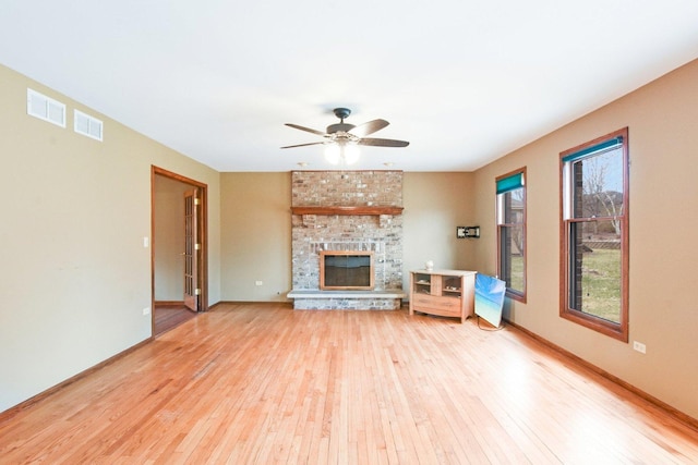 living room featuring light wood finished floors, a fireplace, and visible vents