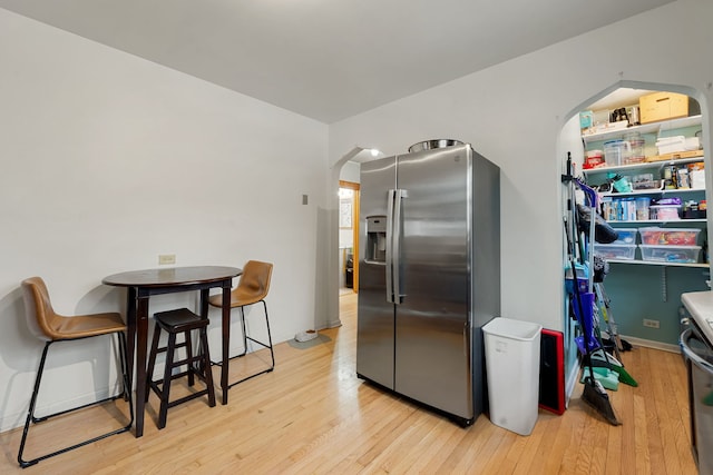 kitchen featuring stainless steel fridge with ice dispenser, light wood-type flooring, and arched walkways