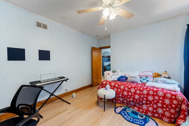 bedroom featuring a ceiling fan, visible vents, and wood finished floors