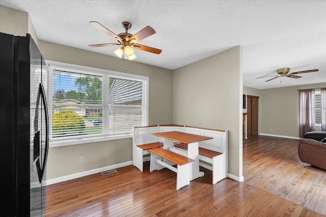 dining area with a ceiling fan, baseboards, a textured ceiling, and hardwood / wood-style flooring