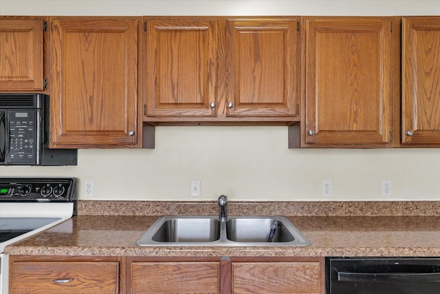 kitchen featuring a sink, dark countertops, brown cabinetry, and black appliances
