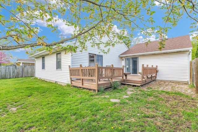 rear view of house featuring a fenced backyard, a deck, and a lawn