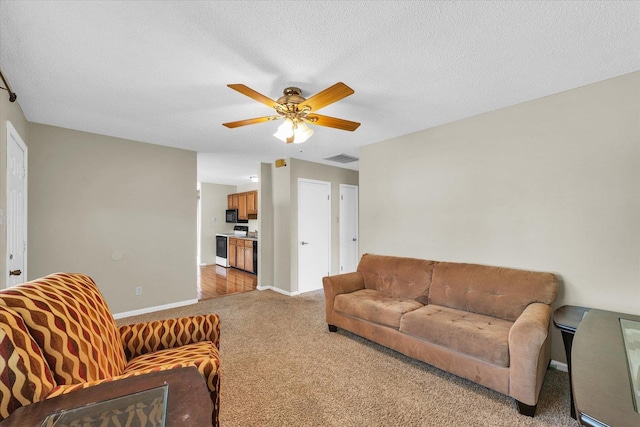 living area featuring light colored carpet, a textured ceiling, visible vents, ceiling fan, and baseboards