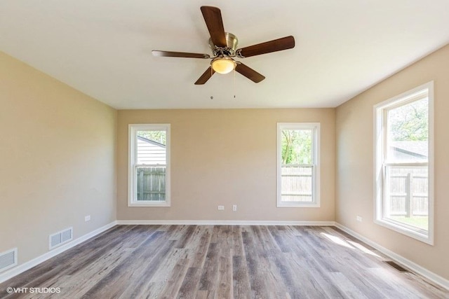 spare room with visible vents, plenty of natural light, and wood finished floors