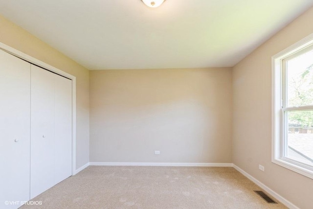 unfurnished bedroom with a closet, visible vents, baseboards, and light carpet