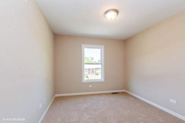 spare room featuring carpet flooring, visible vents, and baseboards