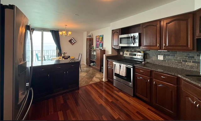 kitchen with a notable chandelier, pendant lighting, dark wood-style flooring, tasteful backsplash, and appliances with stainless steel finishes