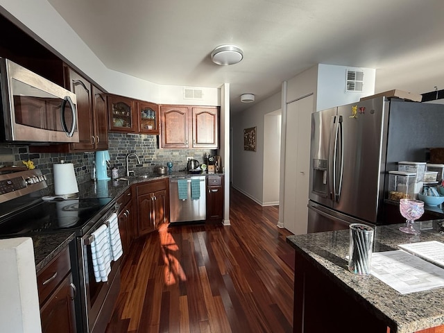 6033 N Sheridan Rd Unit 12B, Chicago, IL 60660 - kitchen with stainless steel appliances, dark wood finished floors, dark stone countertops, decorative backsplash, and glass insert cabinets