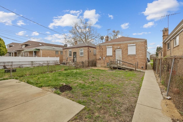 10129 S Indiana Ave, Chicago, IL 60628 - rear view of house with fence private yard, a chimney, brick siding, and a lawn