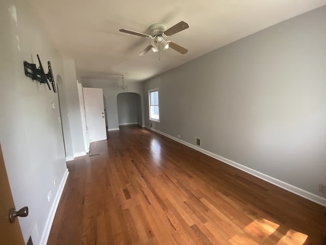 5014 W Strong St, Chicago, IL 60630 - empty room with a ceiling fan, baseboards, dark wood-type flooring, and arched walkways