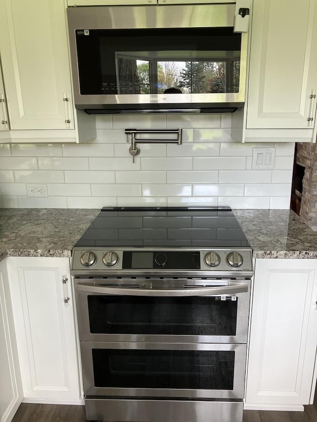 kitchen featuring light stone countertops, white cabinets, appliances with stainless steel finishes, and tasteful backsplash