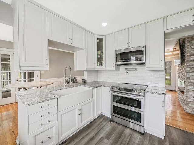 kitchen with light stone countertops, stainless steel appliances, and white cabinets