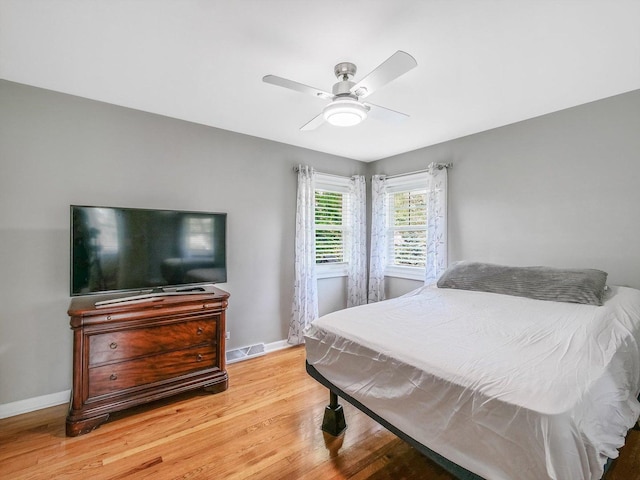 bedroom featuring light wood finished floors, baseboards, a ceiling fan, and visible vents