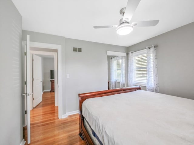bedroom featuring a ceiling fan, visible vents, light wood-style flooring, and baseboards