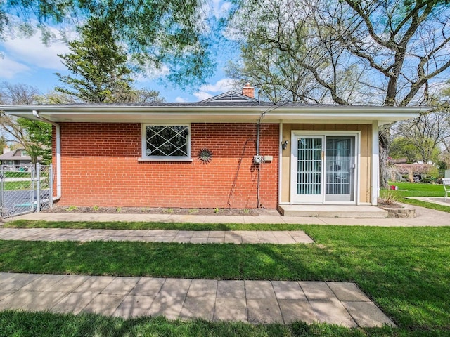 view of front of home featuring fence, a chimney, brick siding, and a front yard