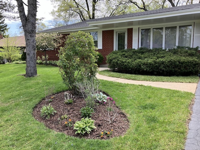single story home with a shingled roof, a front lawn, and brick siding