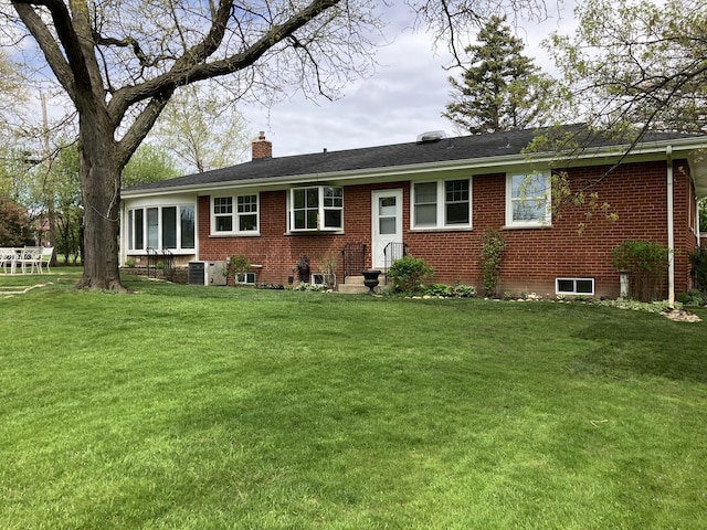 single story home featuring brick siding, a chimney, and a front yard