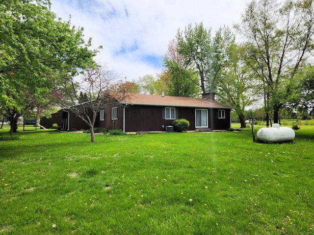 rear view of house featuring a lawn, a chimney, and cooling unit
