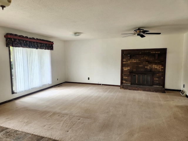unfurnished living room featuring a ceiling fan, baseboards, carpet flooring, a fireplace, and a textured ceiling