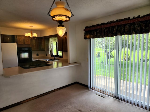 kitchen featuring black appliances, a sink, a chandelier, carpet, and light countertops