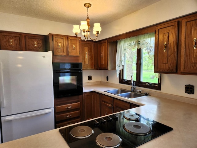 kitchen with black appliances, a sink, light countertops, a chandelier, and pendant lighting