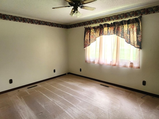 carpeted spare room featuring a ceiling fan, a textured ceiling, and baseboards