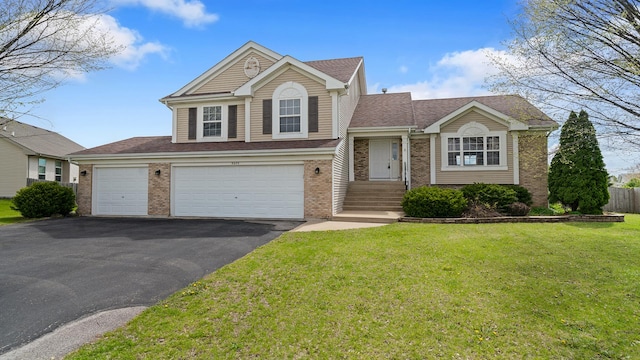 tri-level home with roof with shingles, a front yard, brick siding, and driveway
