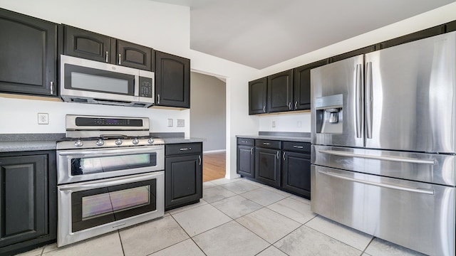 kitchen with dark cabinets, stainless steel appliances, and light tile patterned floors