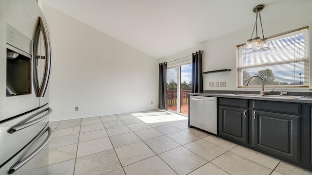 kitchen with lofted ceiling, a notable chandelier, a sink, dark countertops, and stainless steel appliances
