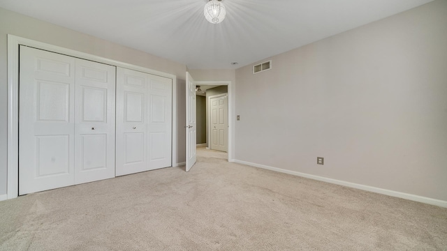 unfurnished bedroom featuring light carpet, a closet, baseboards, and visible vents