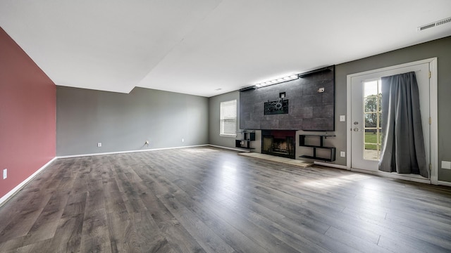 unfurnished living room featuring a wealth of natural light, a fireplace, visible vents, and wood finished floors