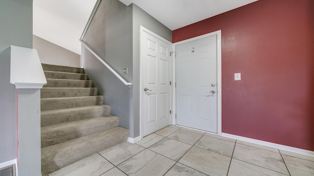 entryway featuring stairway, marble finish floor, and baseboards
