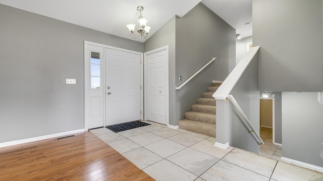 foyer with an inviting chandelier, wood finished floors, visible vents, and baseboards